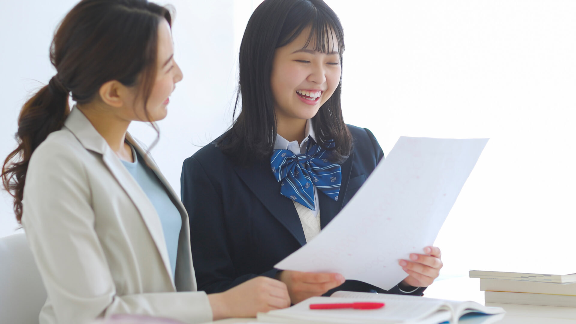 講師と生徒が笑顔でプリントを見ながら話すシーン