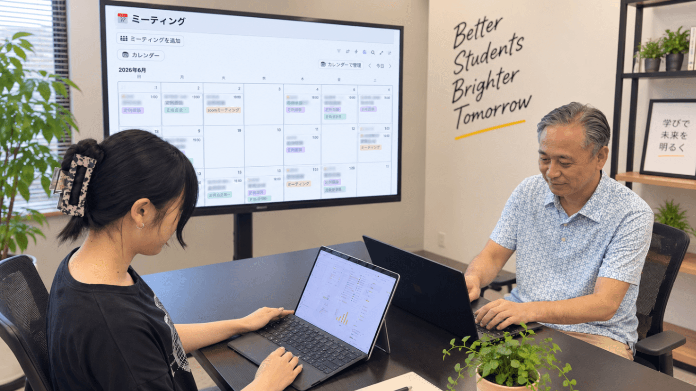 講師と教室長が、Notionの面談カレンダーを大画面に映しながら相談している様子