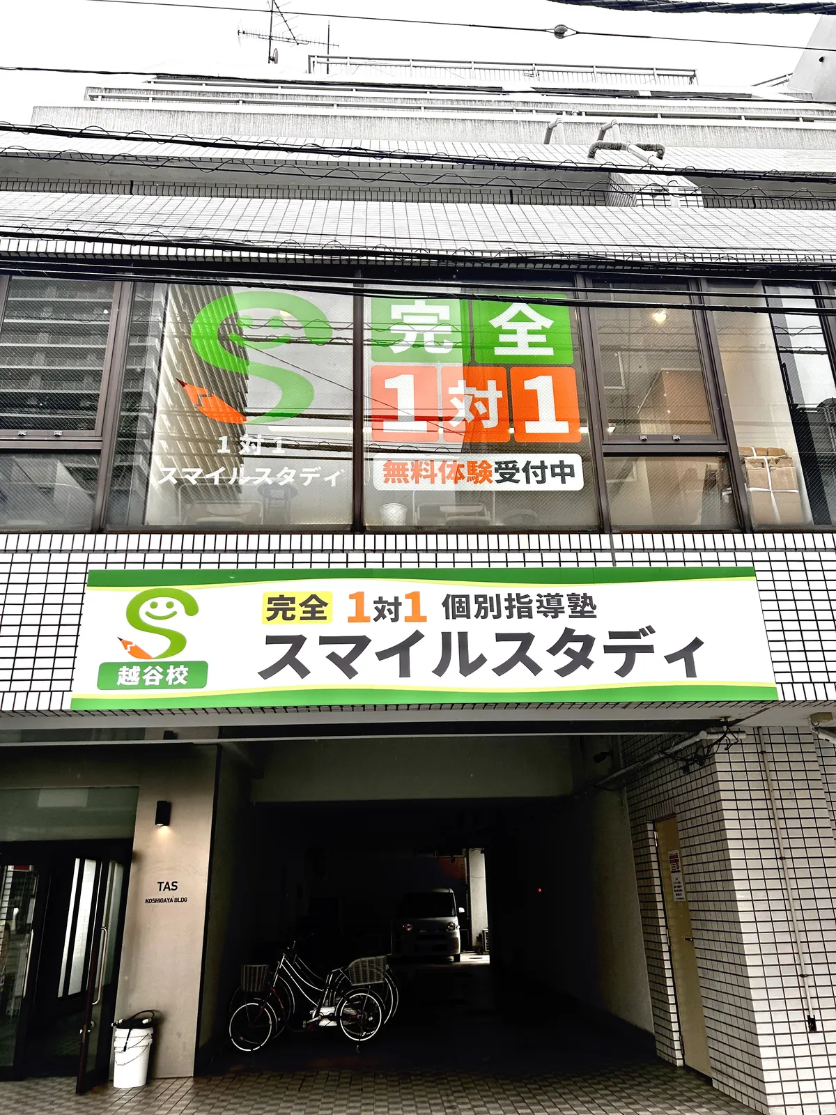 『完全1対1 個別指導塾 スマイルスタディ 越谷校』の看板が見える建物外観